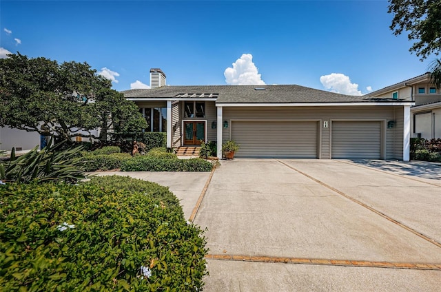 view of front of home with a garage, roof with shingles, and driveway