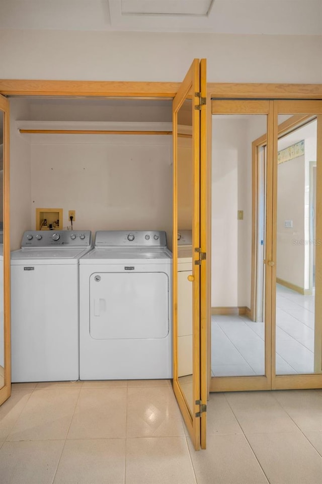 laundry room with laundry area, washing machine and clothes dryer, and light tile patterned floors