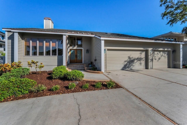 526 Belle Isle Ave, Belleair Beach, FL 33786 - view of front of house with french doors, an attached garage, a chimney, and driveway
