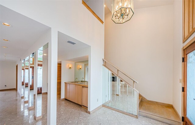 526 Belle Isle Ave, Belleair Beach, FL 33786 - entrance foyer featuring stairway, light tile patterned flooring, a towering ceiling, baseboards, and a notable chandelier