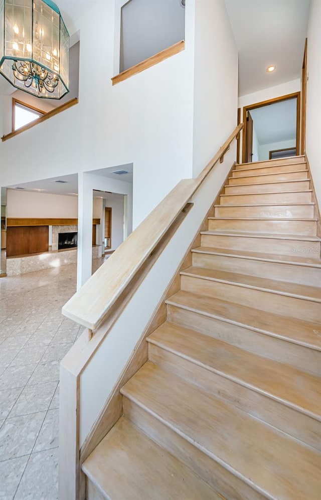 526 Belle Isle Ave, Belleair Beach, FL 33786 - stairway featuring a fireplace, a high ceiling, and an inviting chandelier