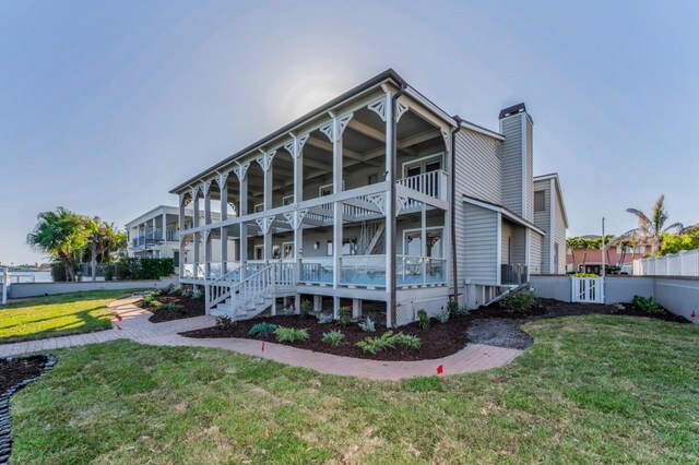 526 Belle Isle Ave, Belleair Beach, FL 33786 - rear view of house featuring a balcony, a chimney, fence, a porch, and a yard