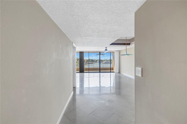 corridor with floor to ceiling windows, tile patterned flooring, and a textured ceiling