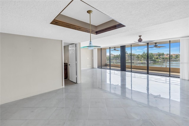 tiled spare room with expansive windows, a water view, and a textured ceiling