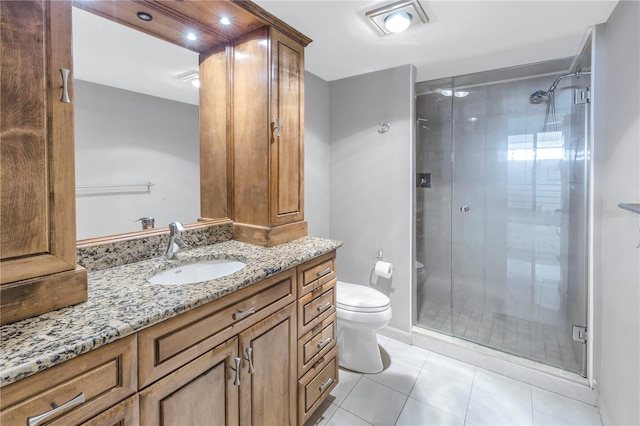 bathroom featuring tile patterned flooring, vanity, toilet, and a shower with door