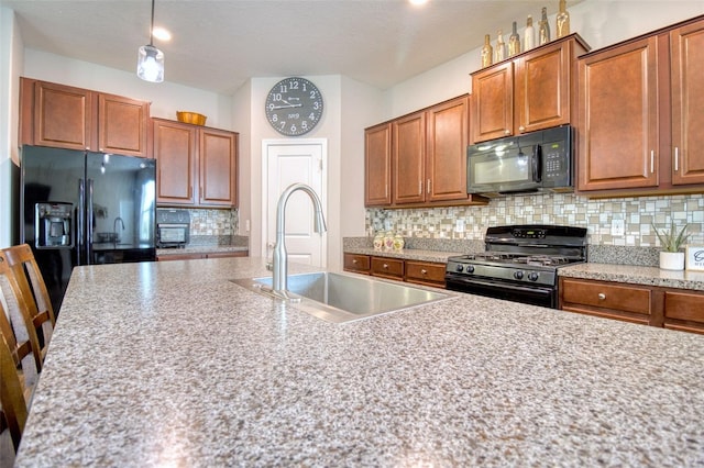 kitchen featuring backsplash, black appliances, sink, decorative light fixtures, and a kitchen bar