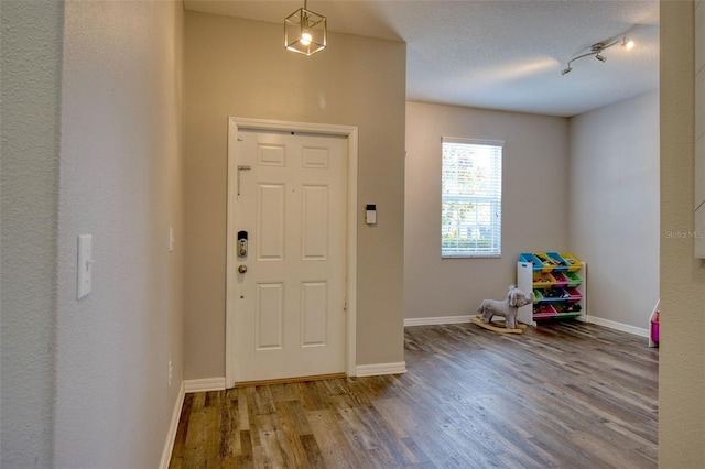 foyer with wood-type flooring, rail lighting, and a textured ceiling