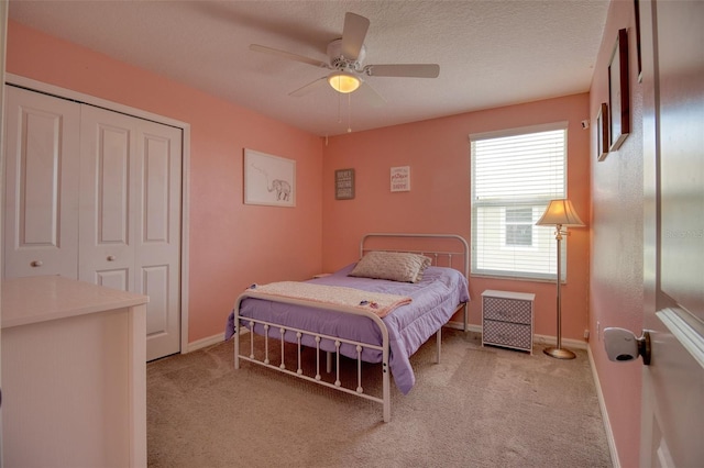 bedroom with ceiling fan, a closet, light carpet, and a textured ceiling