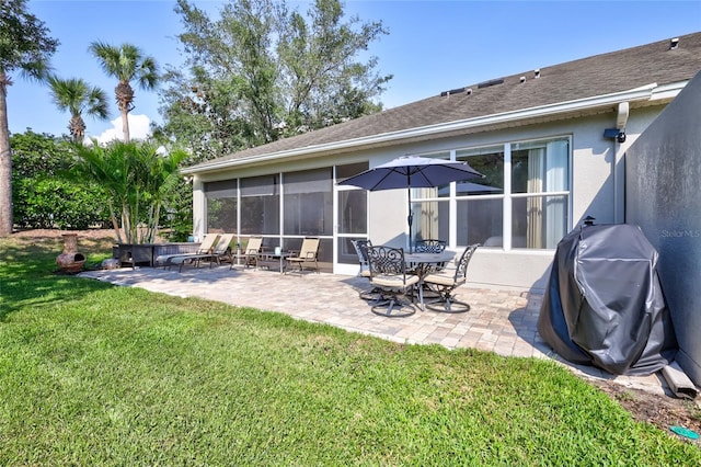 rear view of house with a patio, a lawn, and a sunroom