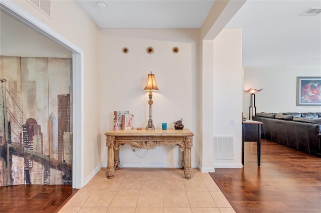 hall with wood finished floors, visible vents, and baseboards