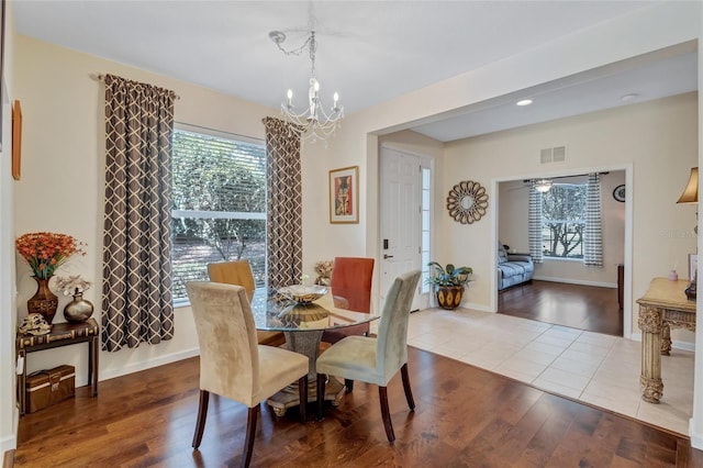 dining area with baseboards, visible vents, an inviting chandelier, and wood finished floors