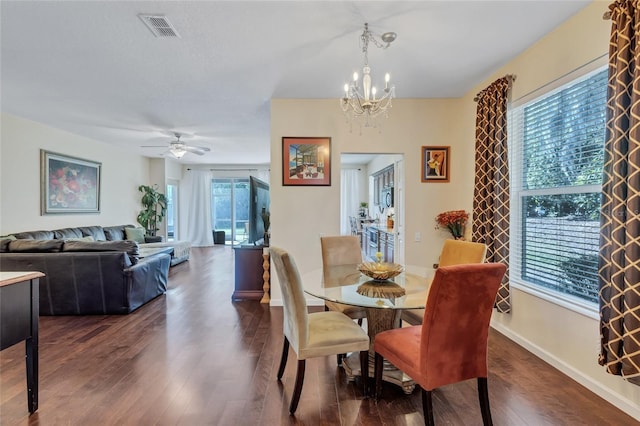 dining area with ceiling fan with notable chandelier, dark wood-type flooring, visible vents, and baseboards