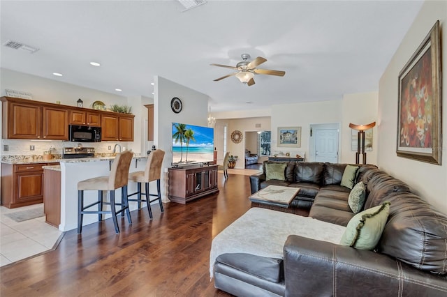 living room with ceiling fan and dark wood-type flooring