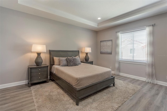 bedroom featuring hardwood / wood-style floors, a tray ceiling, and ornamental molding