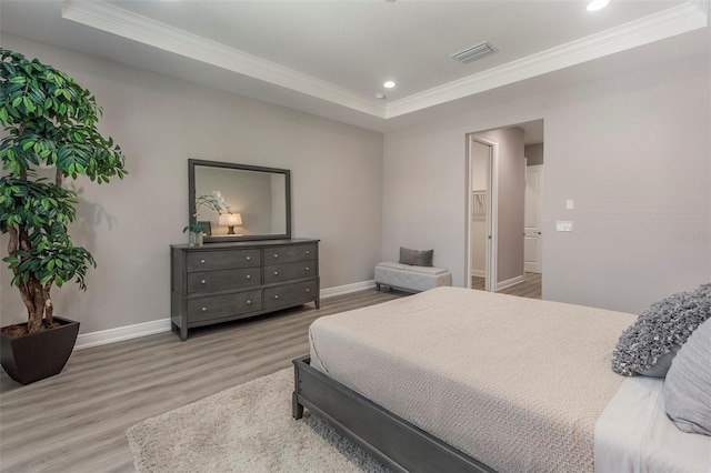 bedroom featuring hardwood / wood-style flooring, ornamental molding, and a tray ceiling