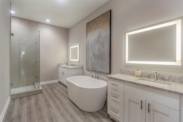 bathroom with plus walk in shower, hardwood / wood-style floors, and vanity