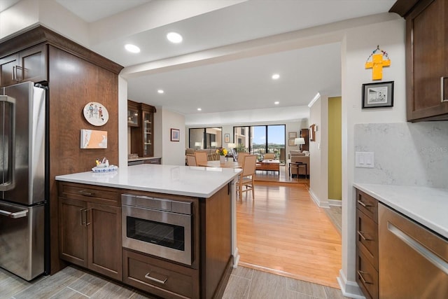 kitchen featuring stainless steel appliances, recessed lighting, light countertops, light wood-style flooring, and decorative backsplash