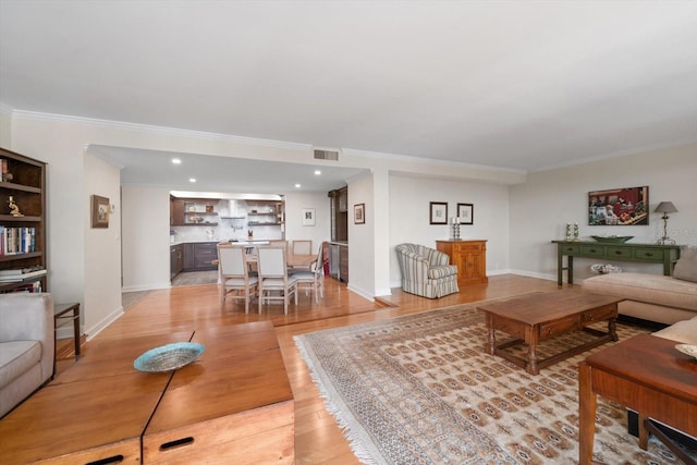 living room featuring crown molding, light wood finished floors, visible vents, and baseboards