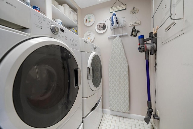 laundry room featuring laundry area, light tile patterned floors, baseboards, and separate washer and dryer