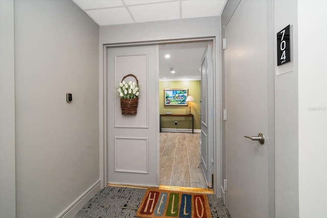 hallway featuring a drop ceiling and baseboards