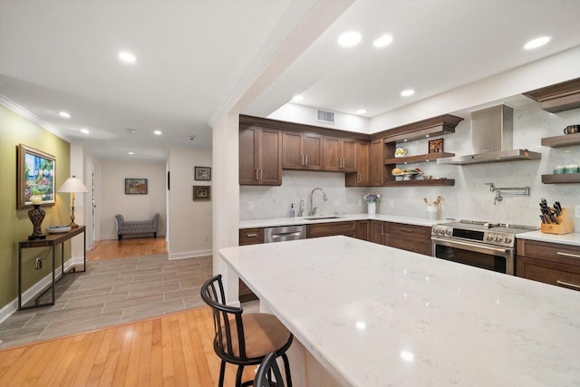 kitchen with light wood finished floors, open shelves, visible vents, appliances with stainless steel finishes, and wall chimney exhaust hood