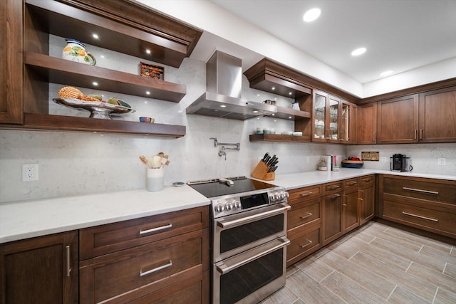 kitchen with wall chimney range hood, double oven range, open shelves, and backsplash