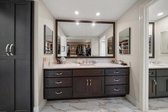 full bath with a walk in closet, marble finish floor, recessed lighting, vanity, and baseboards