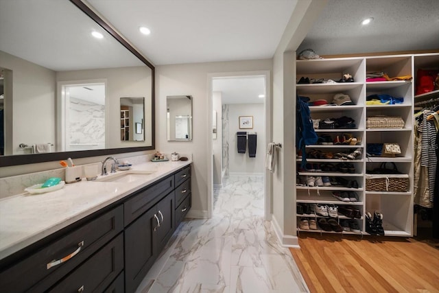 full bathroom with marble finish floor, recessed lighting, a spacious closet, vanity, and baseboards