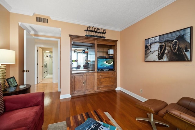 living area featuring dark wood-type flooring, visible vents, crown molding, and baseboards