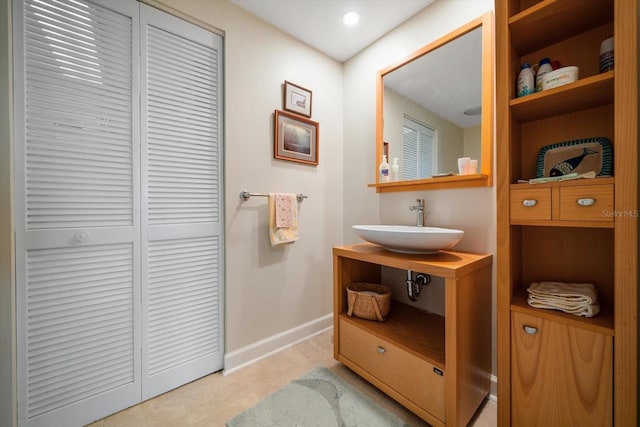 bathroom featuring a closet, a sink, and baseboards