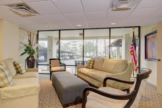 carpeted living area with plenty of natural light, a paneled ceiling, and floor to ceiling windows