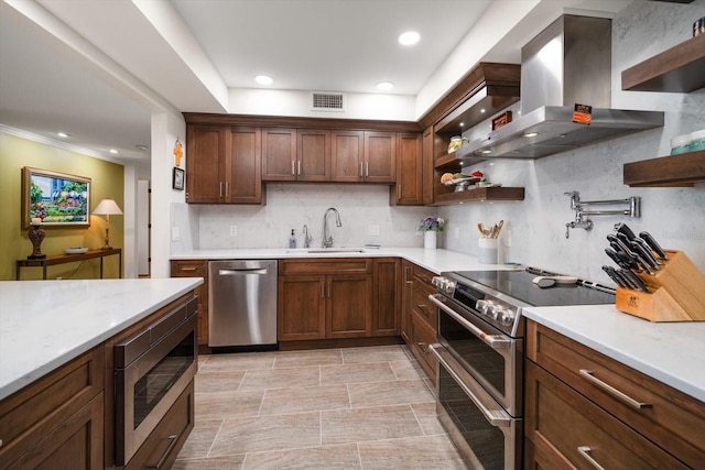 kitchen with visible vents, appliances with stainless steel finishes, light countertops, wall chimney range hood, and a sink