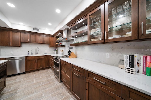 kitchen with tasteful backsplash, visible vents, appliances with stainless steel finishes, a sink, and wall chimney exhaust hood