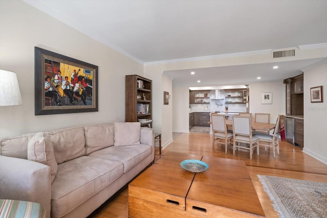 living area with crown molding, recessed lighting, visible vents, light wood-style floors, and baseboards