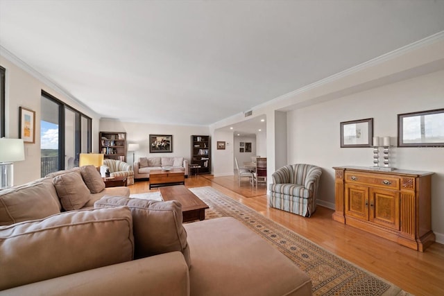 living area with light wood-style floors, visible vents, ornamental molding, and baseboards