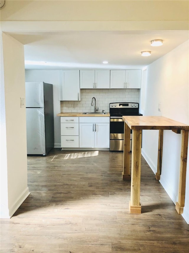 kitchen featuring butcher block counters, backsplash, sink, white cabinetry, and stainless steel appliances