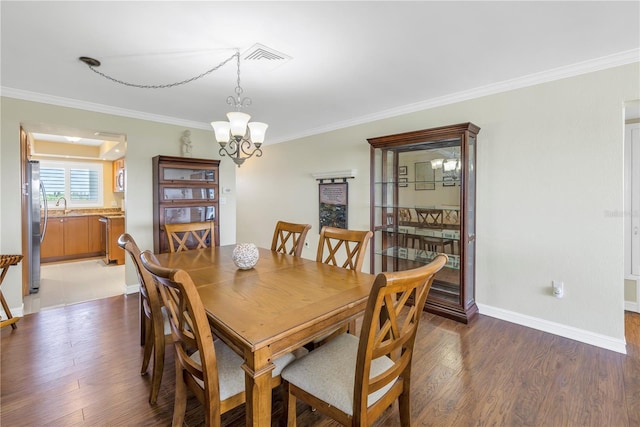 dining area featuring light wood-type flooring, an inviting chandelier, and ornamental molding