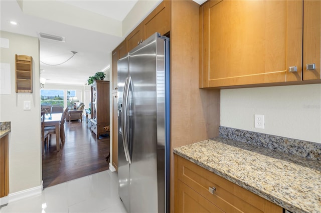 kitchen featuring light tile patterned floors, stainless steel fridge, and light stone countertops