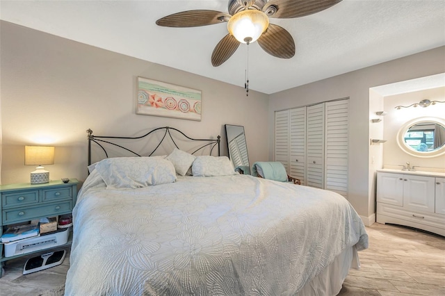 bedroom featuring ceiling fan, sink, ensuite bathroom, light hardwood / wood-style floors, and a closet