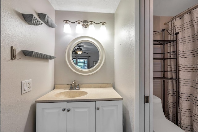 bathroom featuring vanity, ceiling fan, a textured ceiling, and walk in shower