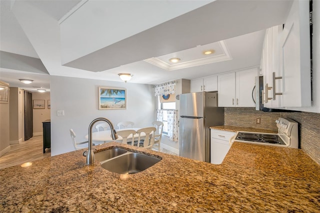 kitchen featuring a raised ceiling, sink, electric range, stainless steel fridge, and white cabinetry