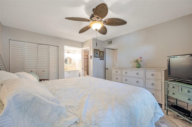 bedroom featuring ceiling fan, a closet, light hardwood / wood-style flooring, and ensuite bath