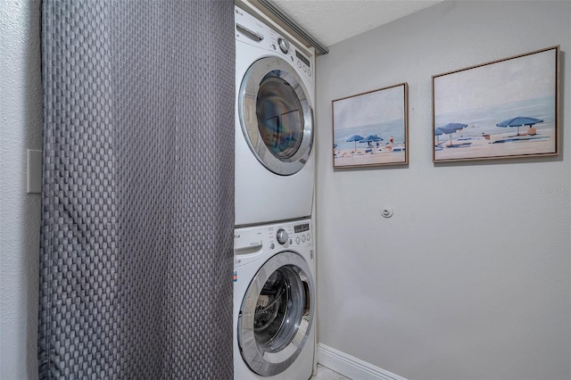 clothes washing area featuring a textured ceiling and stacked washer and clothes dryer