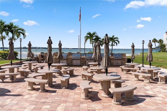 view of home's community with an outdoor kitchen, a water view, and a patio area