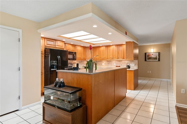 kitchen with black appliances, a center island, light tile patterned floors, and backsplash