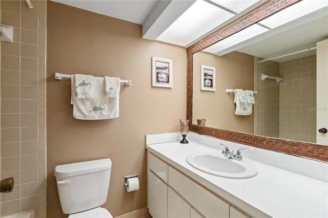 bathroom featuring a tile shower, vanity, and toilet