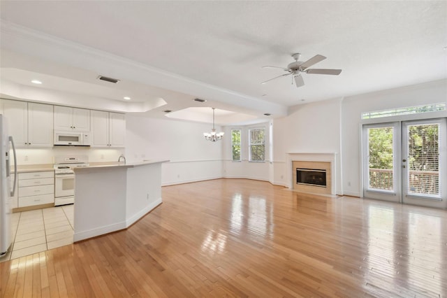 kitchen featuring white appliances, white cabinets, decorative light fixtures, light hardwood / wood-style floors, and ceiling fan with notable chandelier