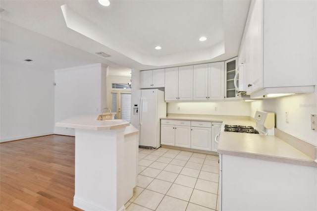 kitchen with stove, a tray ceiling, sink, white refrigerator with ice dispenser, and white cabinets