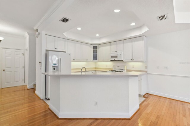 kitchen featuring white appliances, white cabinets, and a raised ceiling