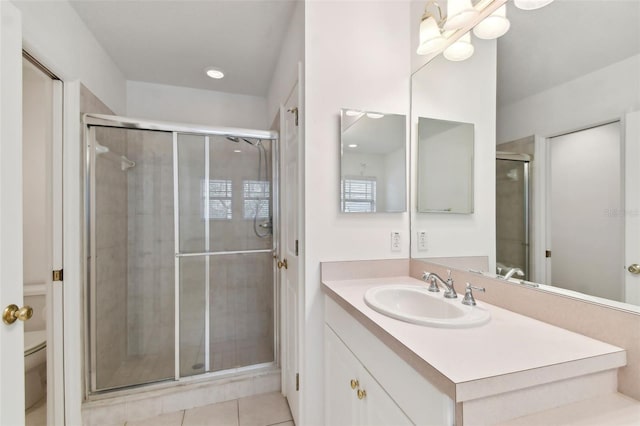 bathroom with tile patterned floors, toilet, vanity, and a shower with shower door